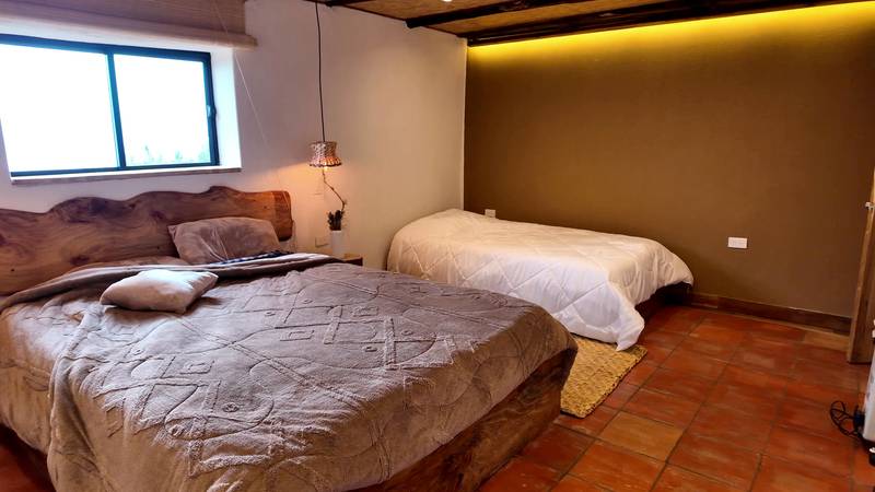 A lodge bedroom with a double bed under a carved wooden headboard and a single bed beside it