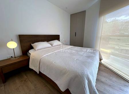 Bedroom with dark wood bed frame, white bedding, two pillows, wooden nightstand with yellow lamp, gray wardrobe, and window with natural light.