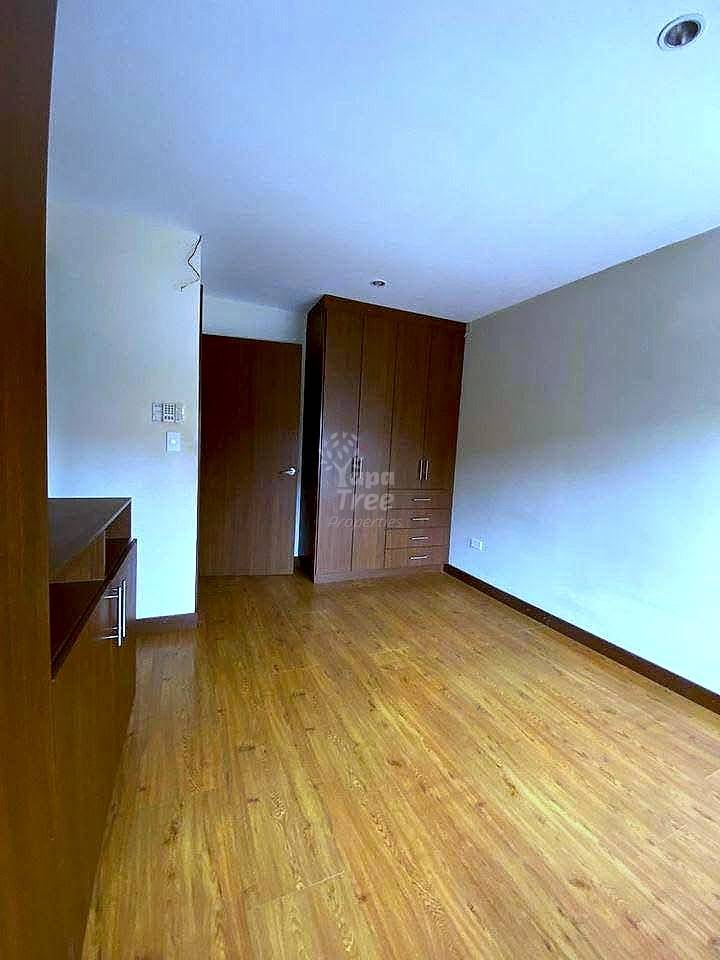 Bedroom with wooden flooring, dark wood wardrobe cabinets, white walls, recessed ceiling light, and built-in shelving on left side.