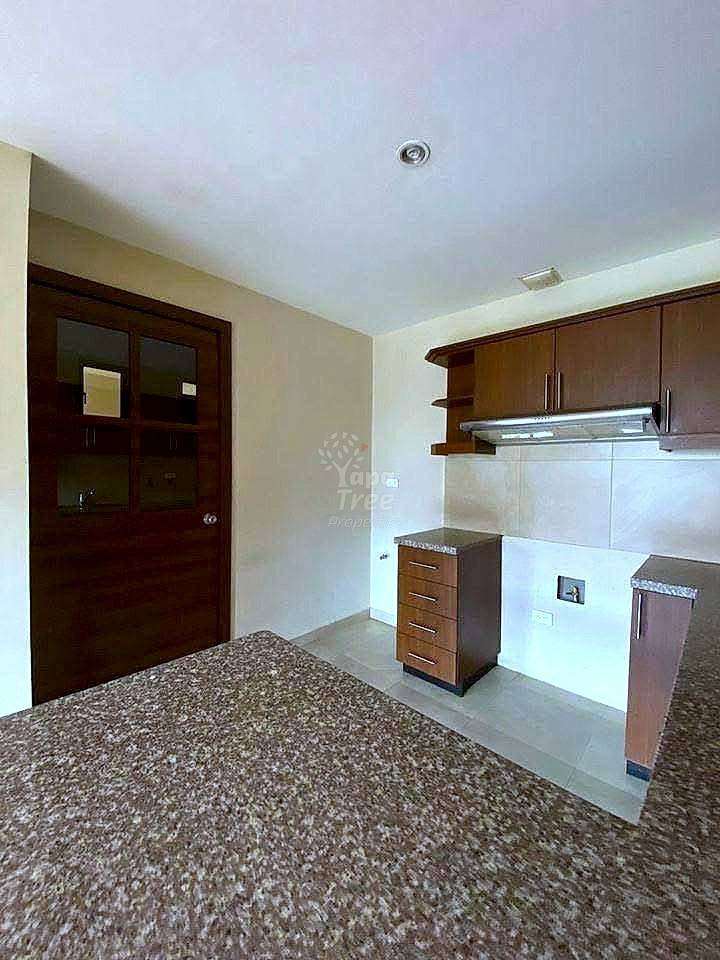 Kitchen with dark wood cabinets, light granite countertops, beige tile backsplash, and light tile flooring.