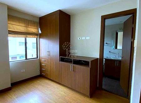 Bedroom with wood flooring, built-in dark wood wardrobes, vanity desk, window with wooden blinds, and doorway to ensuite bathroom