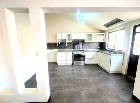 Modern kitchen with white cabinetry, gray tile flooring, stainless steel appliances, dark backsplash, and natural light from windows.
