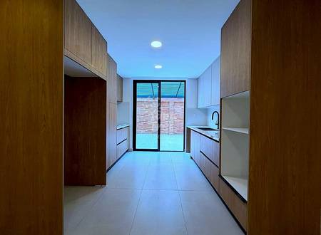 Modern kitchen with wood cabinetry on both sides, tile flooring, recessed lighting, and glass doors opening to brick patio.
