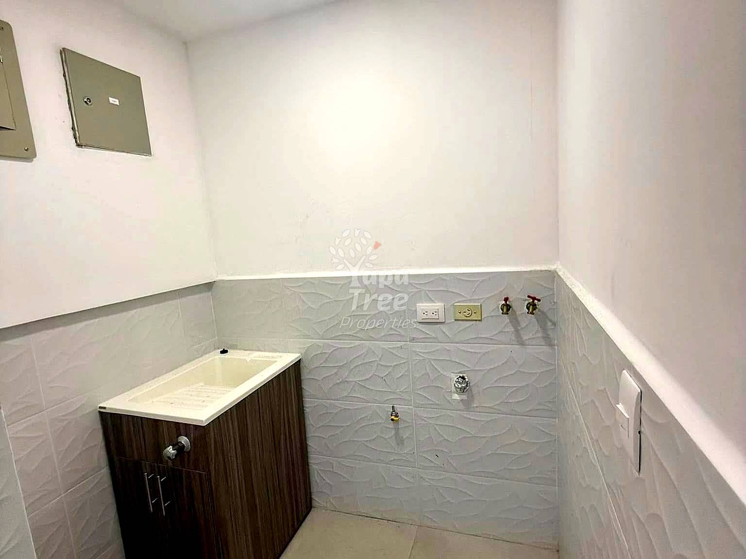 Small bathroom with white upper walls, gray textured tile lower walls, dark wood vanity with white sink, and wall-mounted electrical outlets.