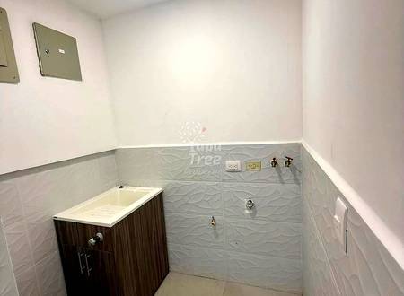 Small bathroom with white upper walls, gray textured tile lower walls, dark wood vanity with white sink, and wall-mounted electrical outlets.