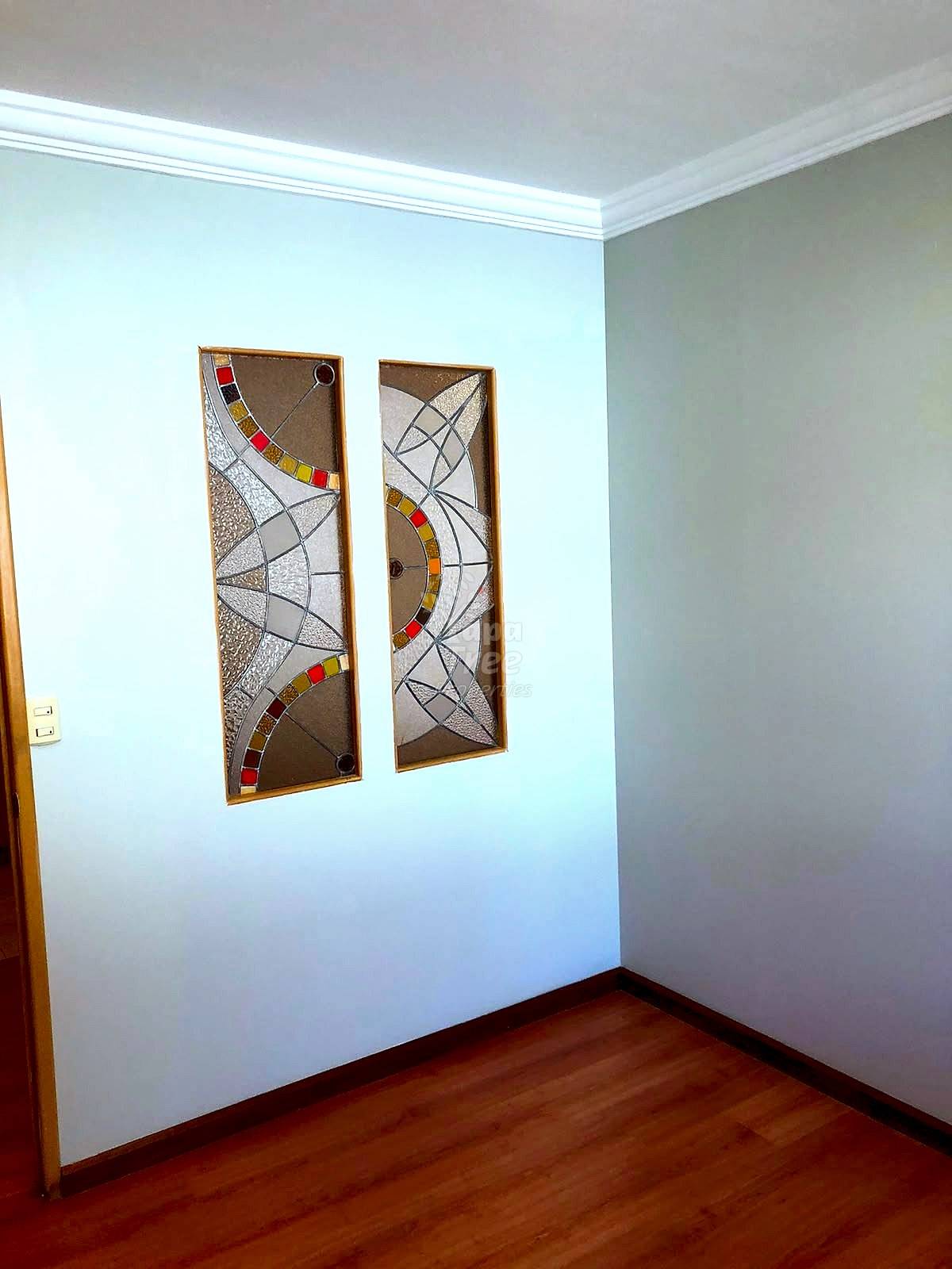 Room corner with white walls, crown molding, wooden floor, and two framed abstract artworks with geometric patterns and colored accents.