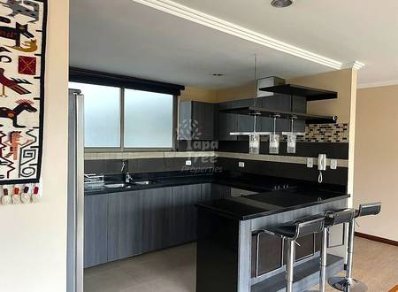 Cocina moderna con gabinetes oscuros, encimeras de granito negro, azulejos mosaico en salpicadero, isla con asientos de barra y ventana grande con vidrio esmerilado.