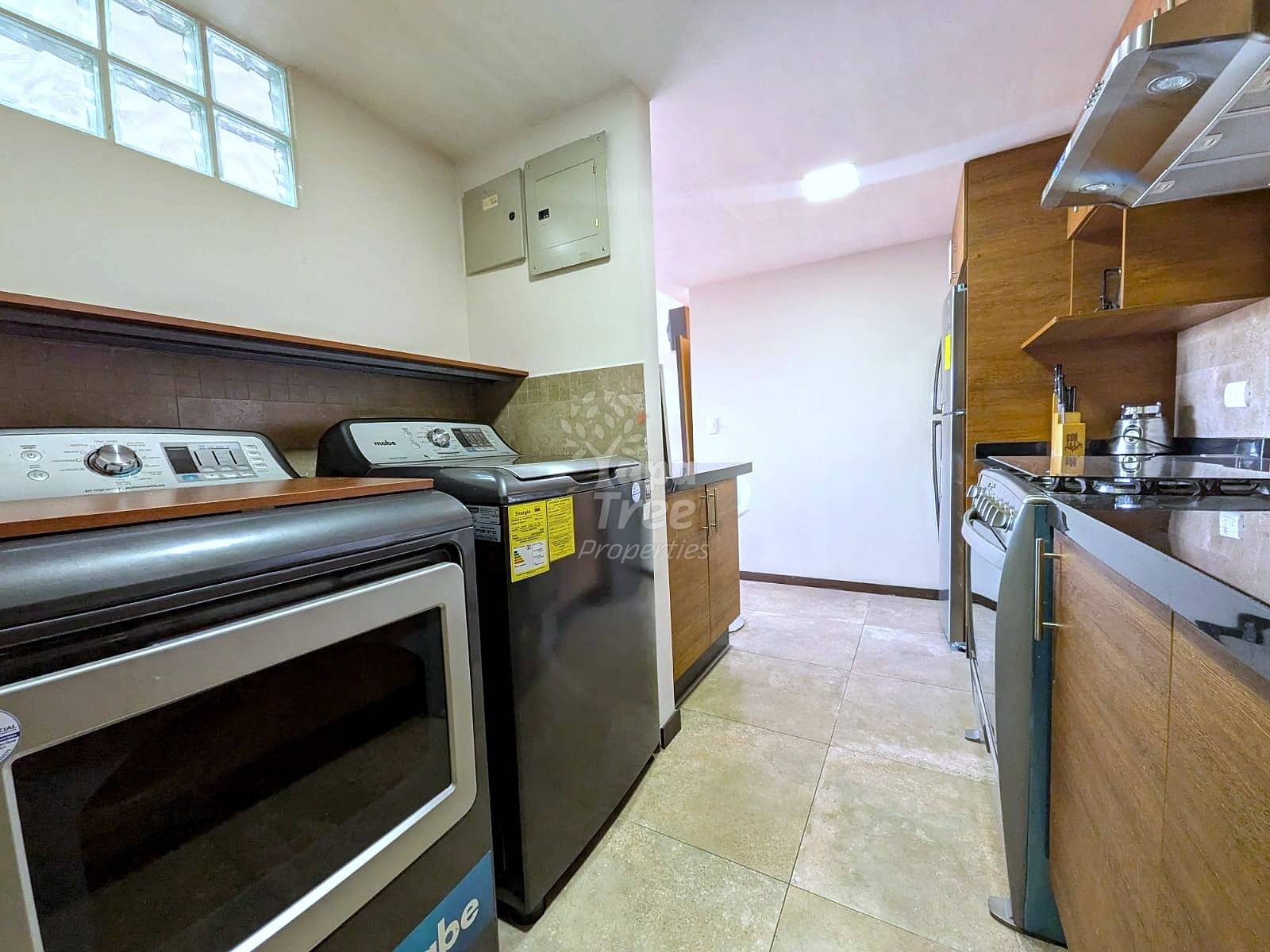 Kitchen with tile flooring, wooden cabinets, stainless steel appliances including double wall oven and gas range, and window with natural light above.