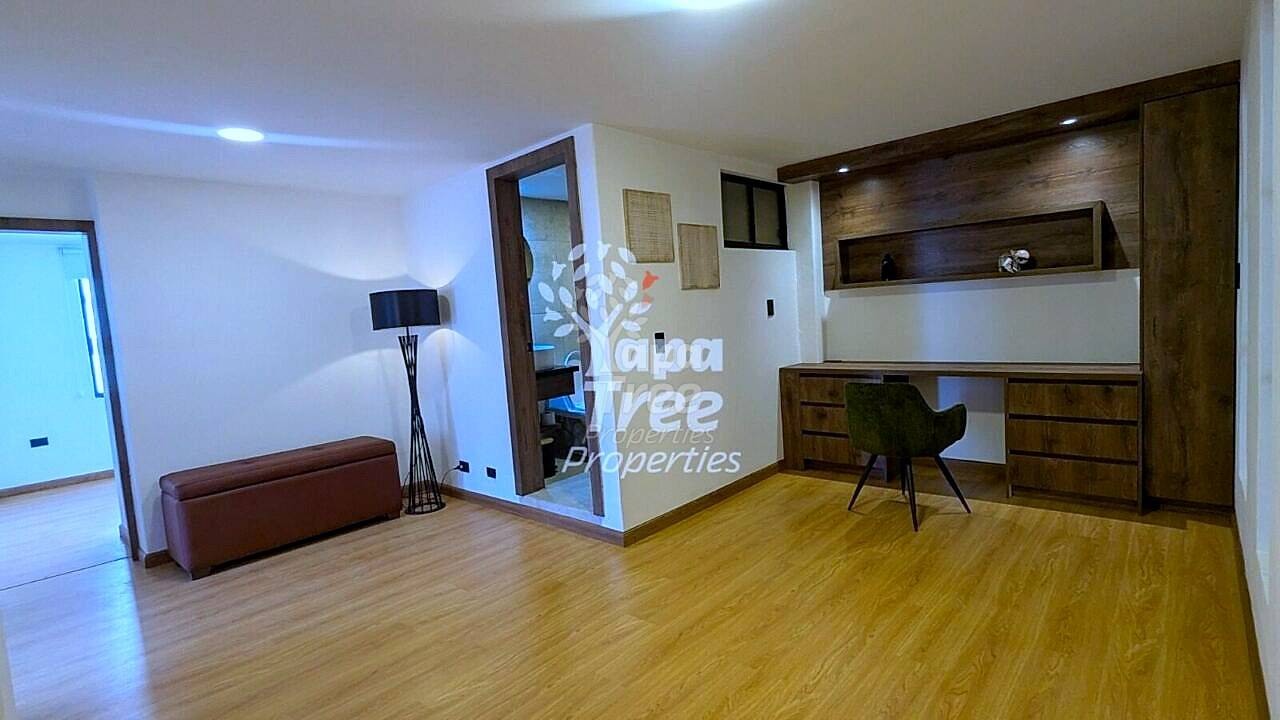 Living room with wood flooring, burgundy bench seating, floor lamp, and wooden built-in desk unit with dark wood shelving and recessed lighting