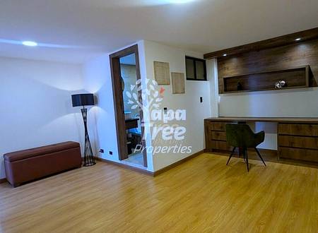 Living room with wood flooring, burgundy bench seating, floor lamp, and wooden built-in desk unit with dark wood shelving and recessed lighting