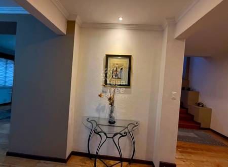 Entryway hallway with white walls, recessed ceiling light, decorative console table with vase, and framed artwork.