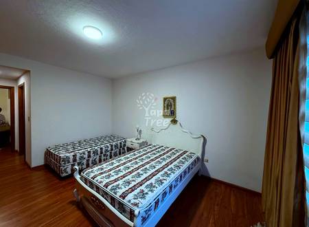 Bedroom with two twin beds with patterned mattresses, wooden headboard, white walls, ceiling light, and brown curtains.