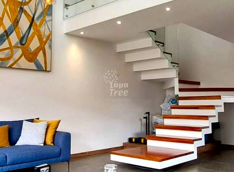 Modern living room with floating staircase, white and wood steps, blue sofa, pendant lighting, and marble coffee table.