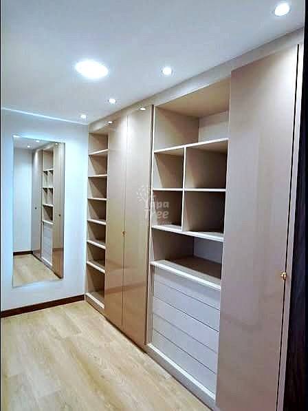 Walk-in closet with built-in wood shelving, mirrored doors, recessed ceiling lights, and light wood flooring.
