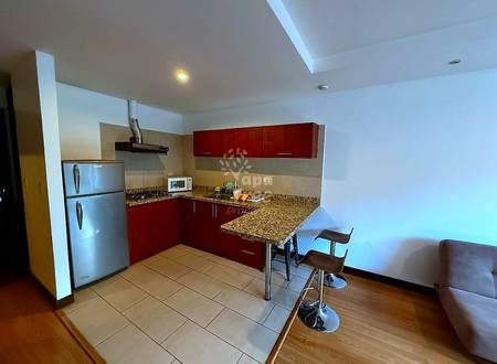 Modern cocina with dark red cabinets, granite countertop, stainless steel appliances, and breakfast bar with two stools, connected to living area.