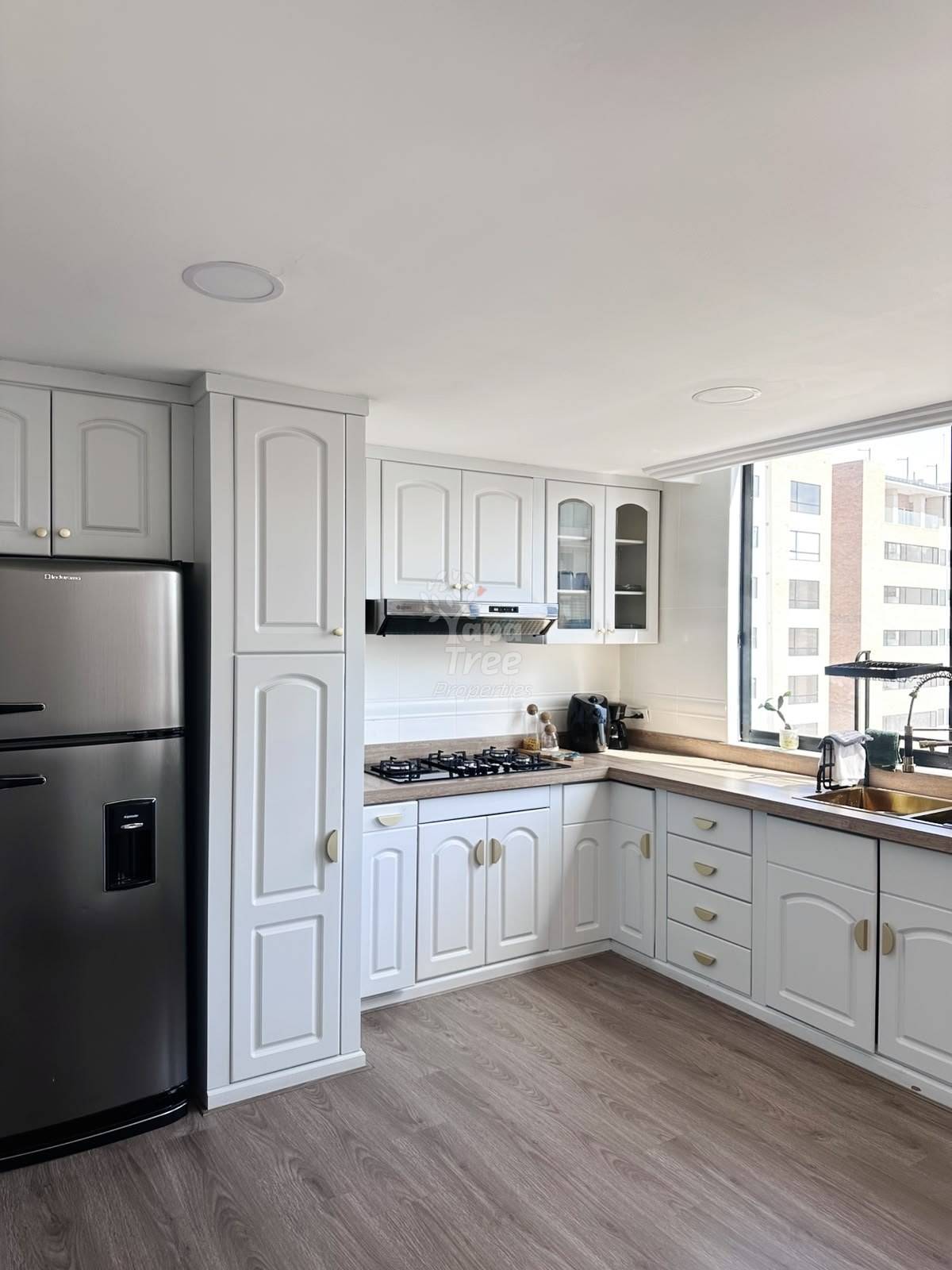 Modern kitchen with white cabinetry, stainless steel appliances, gas cooktop, wood countertops, and wood-grain flooring with recessed ceiling lights.