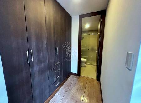 Bedroom hallway with dark wood wardrobe cabinets, wooden flooring, and open bathroom door with toilet visible.