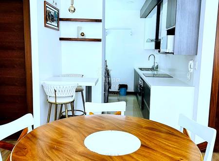 Open kitchen and dining area with round wooden table, white chairs, white cabinetry, stainless steel appliances, and pendant lighting.