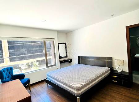 Bedroom with queen bed, black nightstands, blue chair, desk, wood flooring, large window, recessed lighting, and white ceiling.