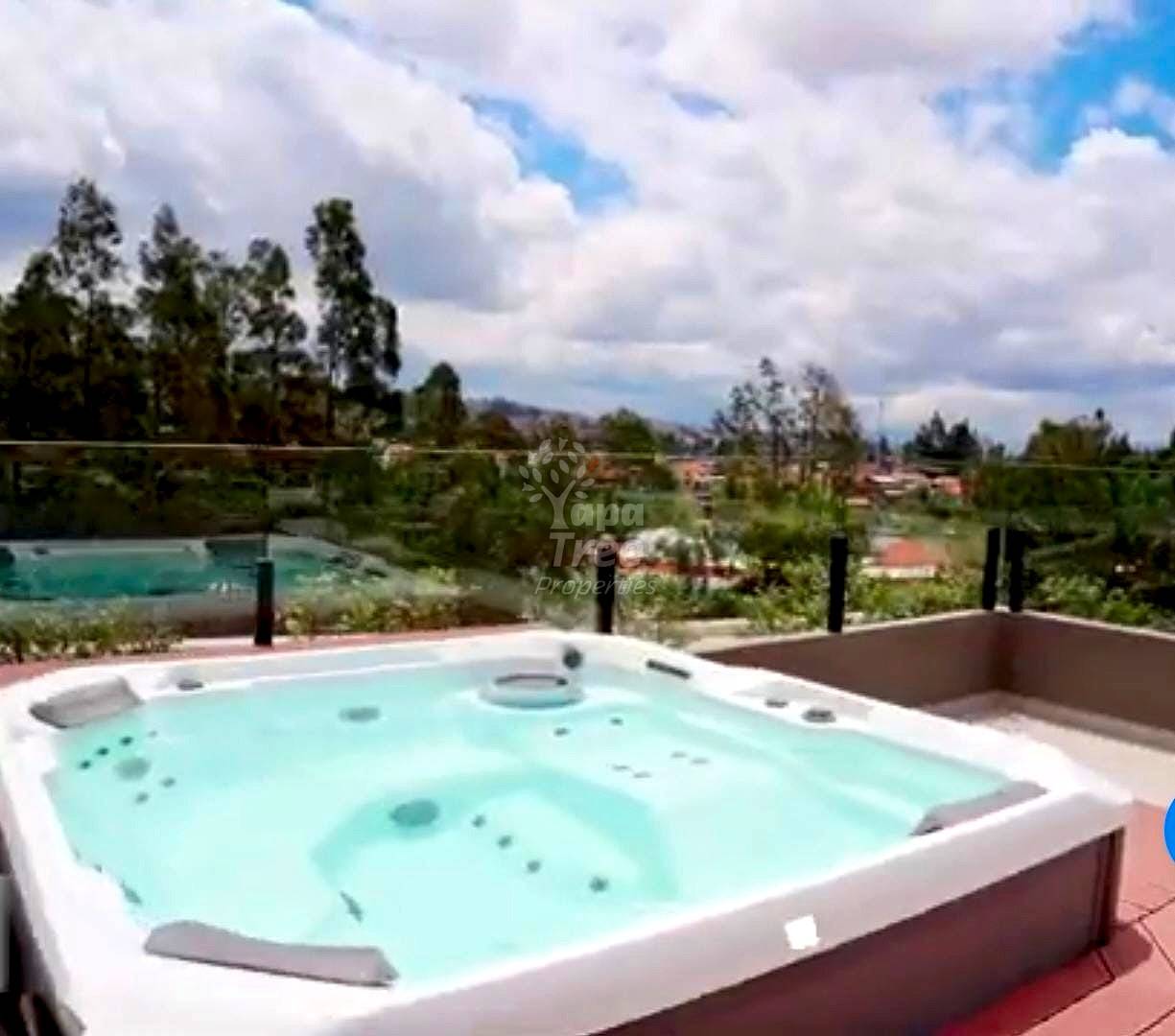Rooftop terrace with built-in hot tub, metal railing, mountain and valley views under cloudy sky.
