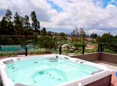 Rooftop terrace with built-in hot tub, metal railing, mountain and valley views under cloudy sky.