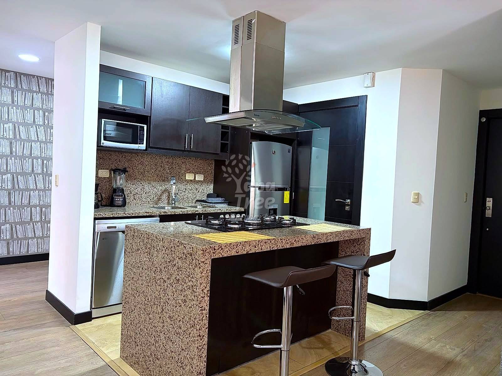 Modern cocina with dark cabinetry, granite countertops, stainless steel appliances, island with seating, and overhead range hood.