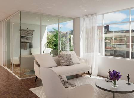 Modern departamento living room with cream sofa, glass-enclosed bathroom, large windows overlooking Cuenca cityscape, and terracotta tile flooring.