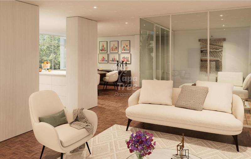 Modern living room with cream sofa, accent chair, wooden herringbone flooring, and glass partition wall leading to bedroom area.