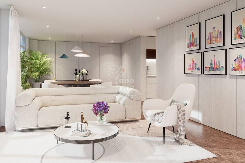 Modern living room with cream curved sofa, white armchair, round white coffee table, pendant lights, wooden dining table, potted plant, and framed cityscape artwork on light walls.