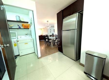 Kitchen with stainless steel refrigerator, white dryer, tile flooring, dark cabinetry, and open view to dining area with table and chairs