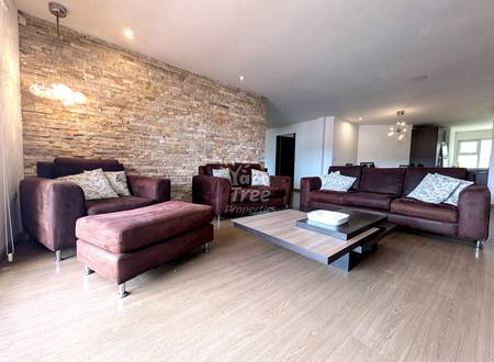 Living room with burgundy upholstered sofas, wood coffee table, light wood flooring, and textured brick accent wall with pendant lighting.