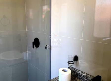 Bathroom with ceramic tile walls, glass shower enclosure with black handle, granite countertop, and toilet paper roll.