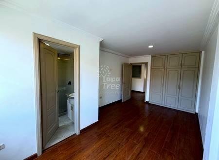 Bedroom with dark wood flooring, white walls, built-in wardrobe doors, ensuite bathroom with glass shower enclosure, and recessed ceiling lights.