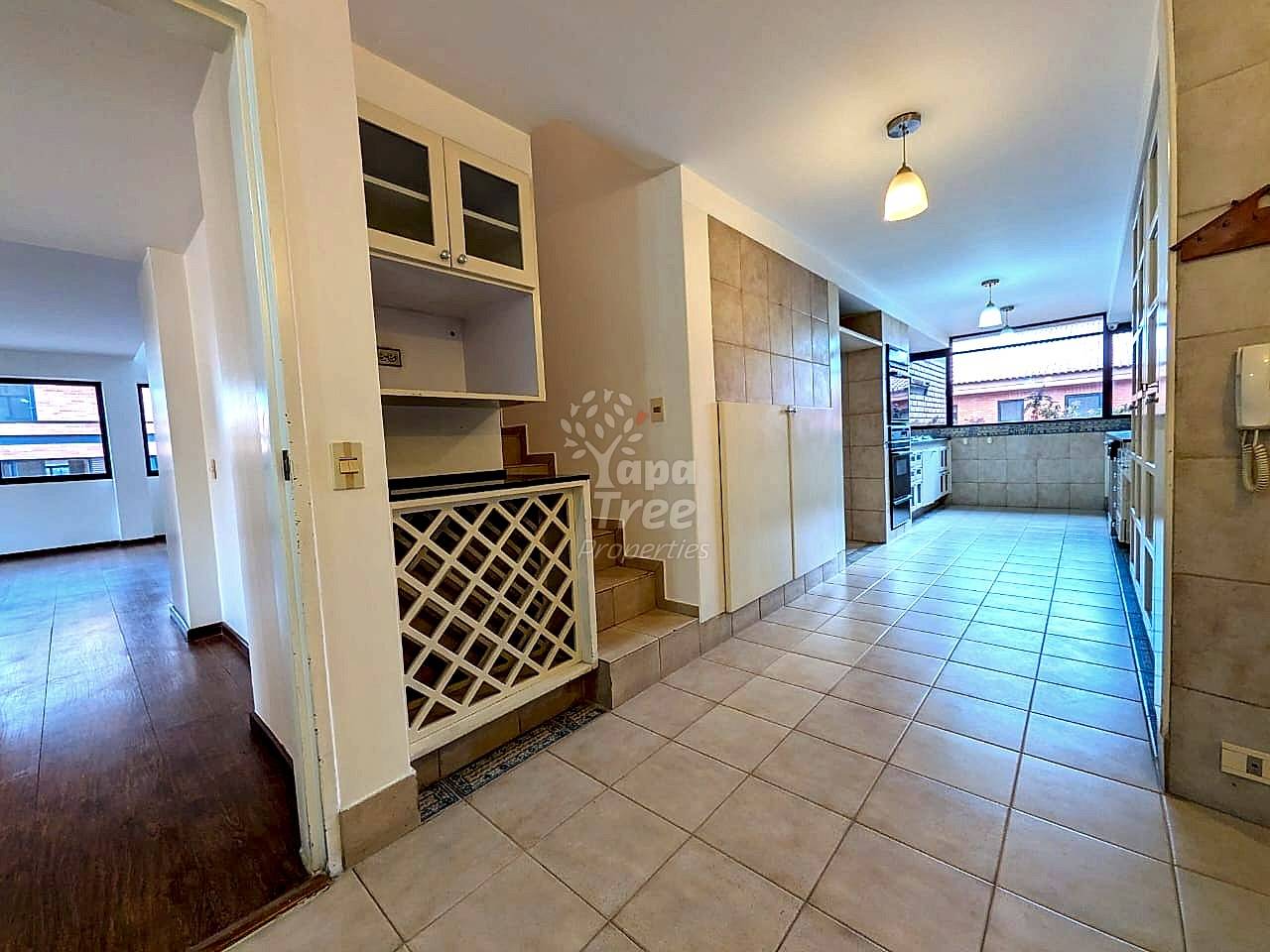 Kitchen with cream cabinetry, tile flooring, open shelving, and decorative wine rack insert on built-in unit.