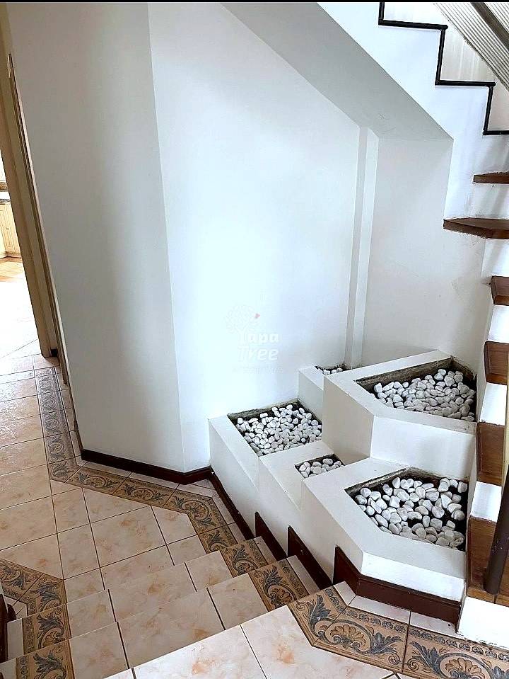 Staircase landing with white walls, terracotta tile floor, and built-in white planters filled with white stones beside wooden steps.