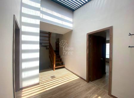 Open living area with wooden staircase, wood plank flooring, white walls, and striped skylight casting natural light from above.