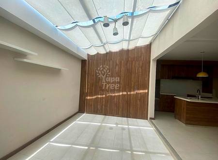Open-plan living area with retractable skylight, white ceramic tile flooring, wood-grain wardrobe doors, and dark wood kitchen counter visible on the right.