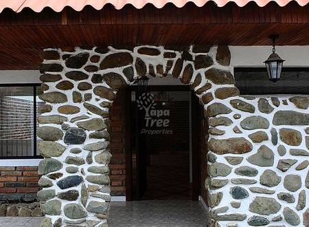 Stone and brick exterior entrance with corrugated metal roof, wooden soffit, hanging lantern, and tile walkway.
