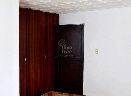Bedroom with geometric wood floor, dark wood wardrobe, black door, white walls, and recessed ceiling lights.
