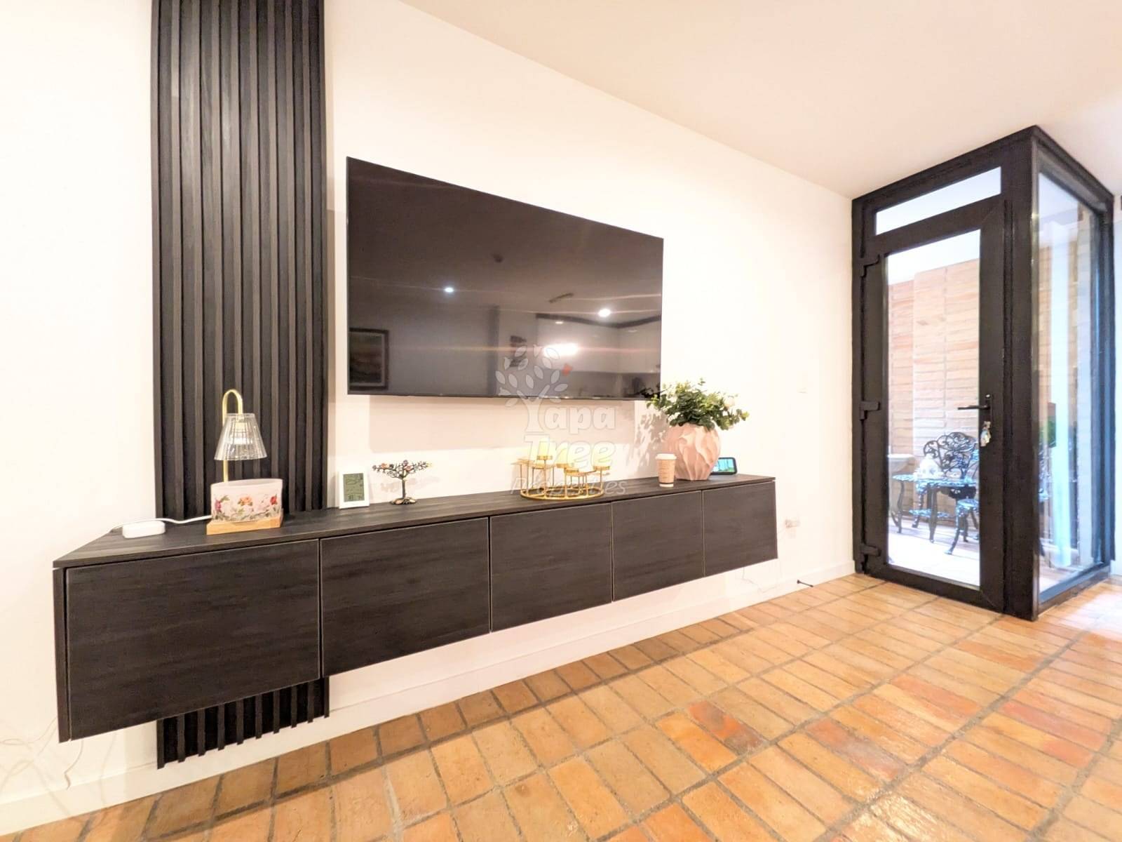 Living room with terracotta tile floor, dark wood built-in cabinet with mirror backsplash, gray curtains, and black glass door to patio.