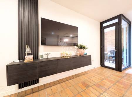 Living room with terracotta tile floor, dark wood built-in cabinet with mirror backsplash, gray curtains, and black glass door to patio.